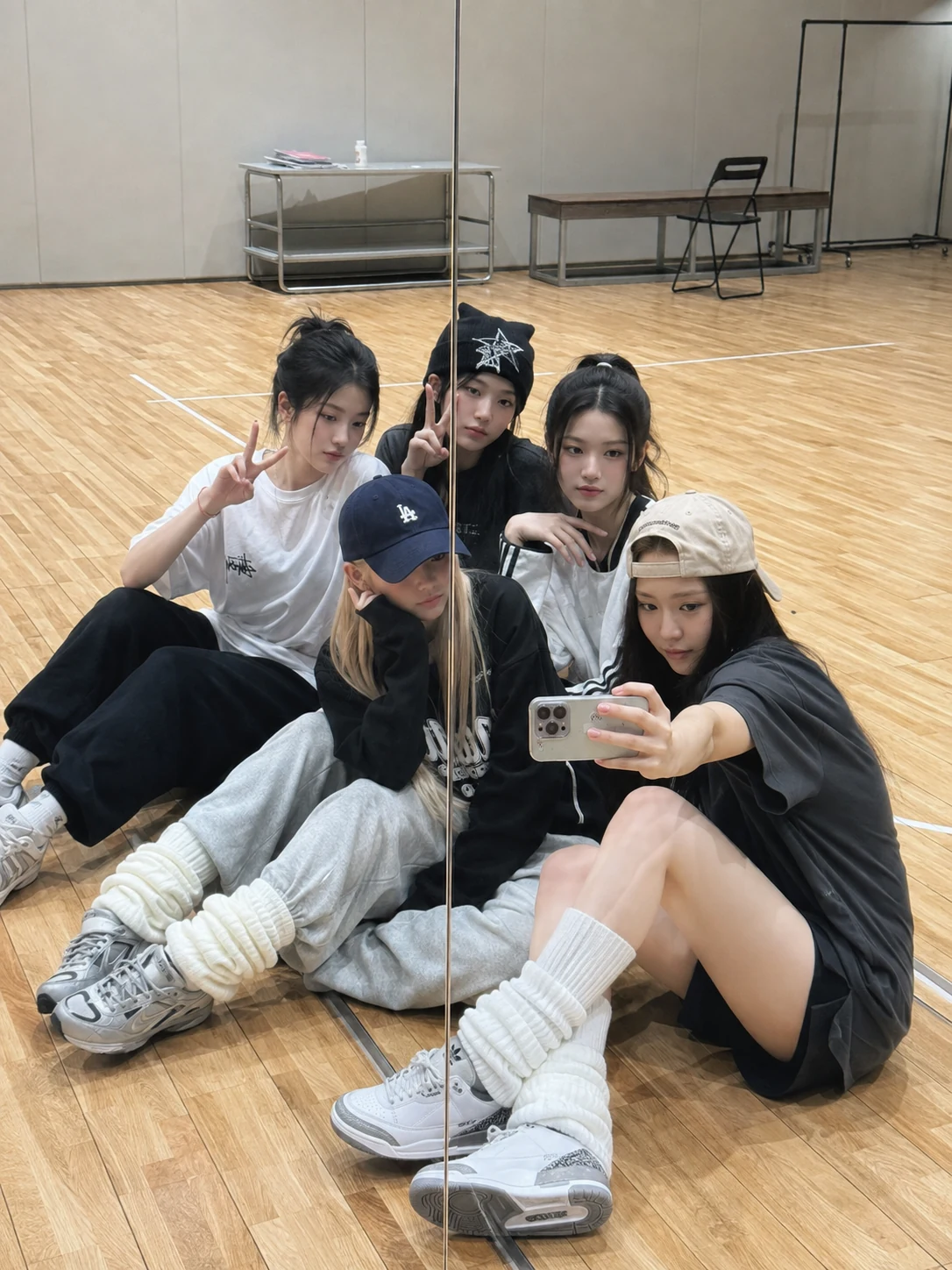 Five-member fictional idol trainee group taking a mirror selfie in a practice room